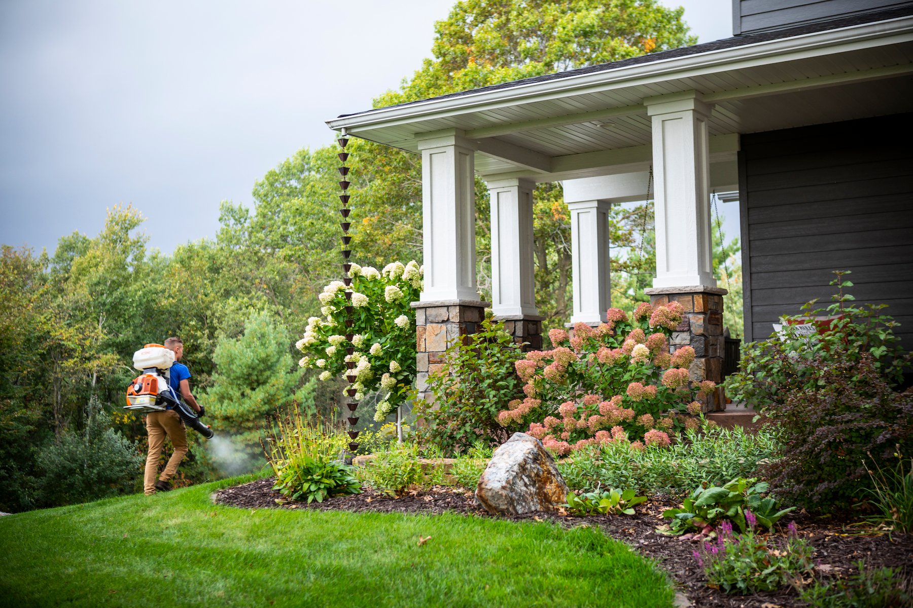 pest control technician spraying mosquito barrier spray to a planting bed