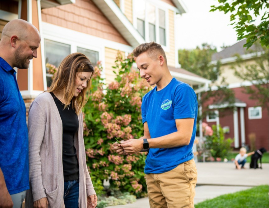 lawn care team inspects grass and meets with clients