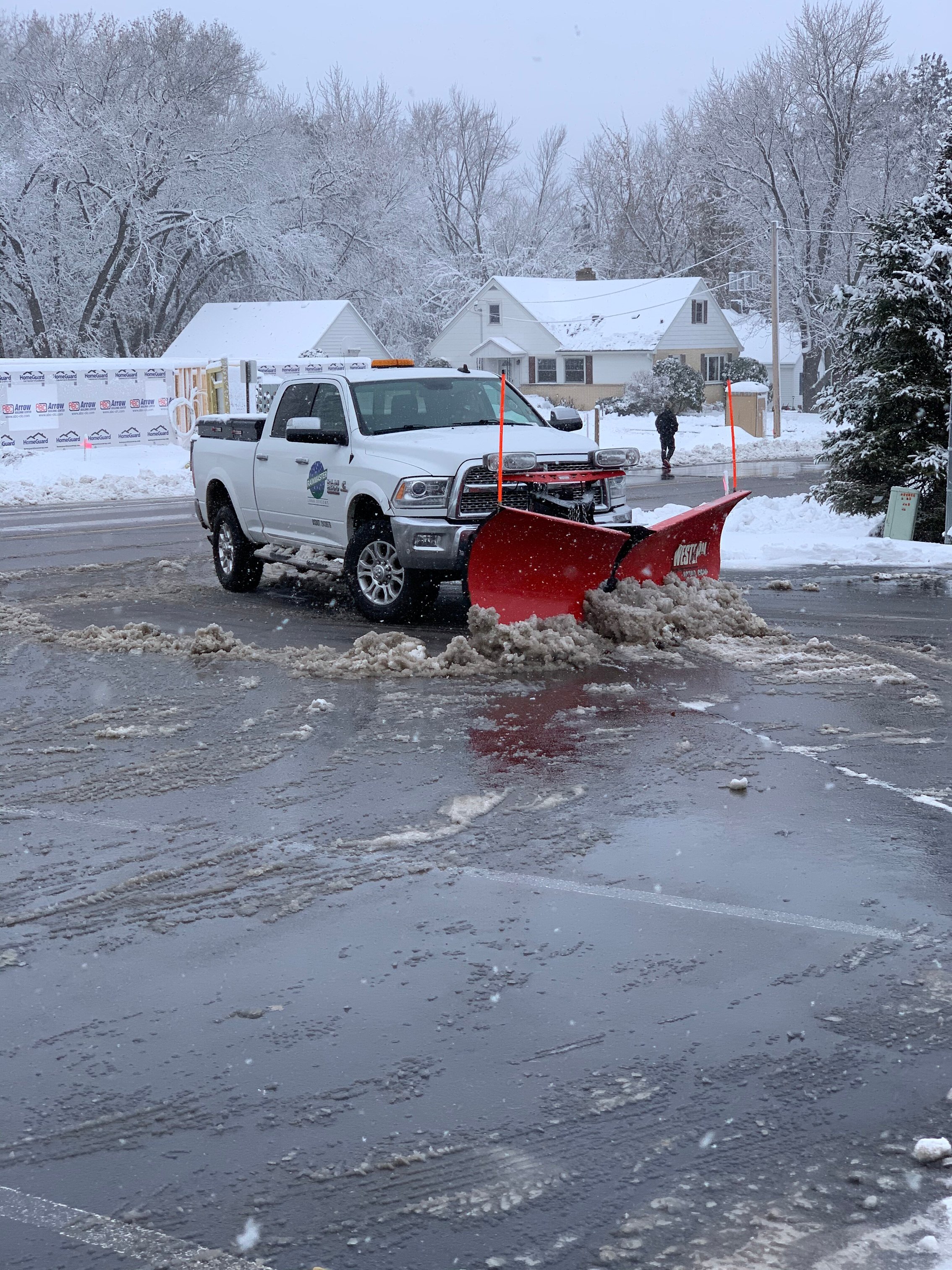 commercial snow removal truck plowing a parking lot