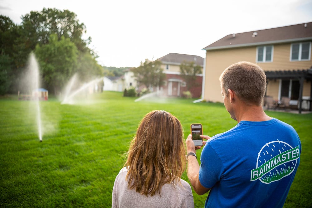 technician shows woman how to operate lawn sprinkler system