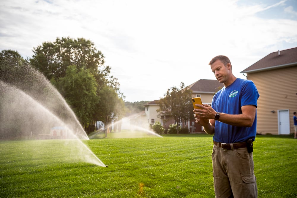irrigation team runs sprinkler system zones with phone