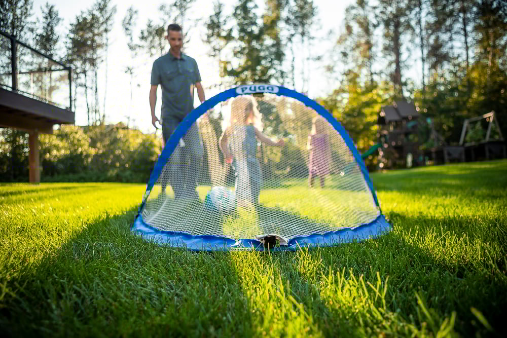 children and parent play soccer on green grass