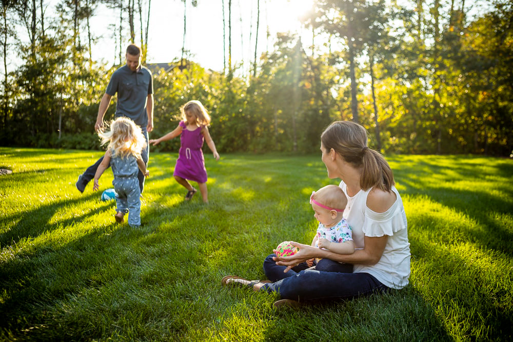 family sits and plays in healthy green grass