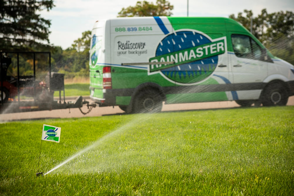 irrigation van in road while sprinklers water lawn