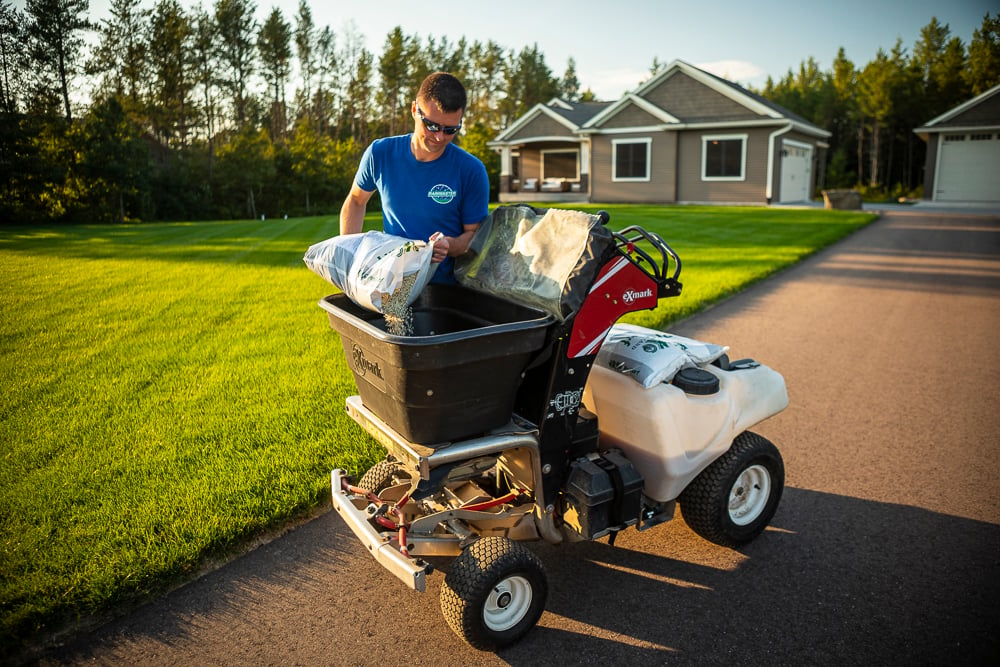 lawn care technician filling lawn machine with granular fertilizer