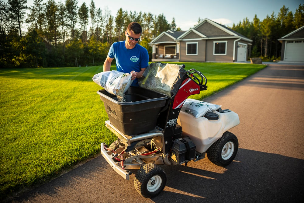 lawn care expert pours fertilizer into spreader