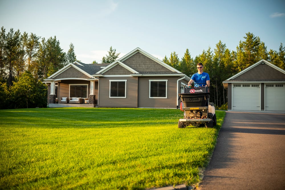 lawn care technician spreading granular fertilizer on a minnesota lawn