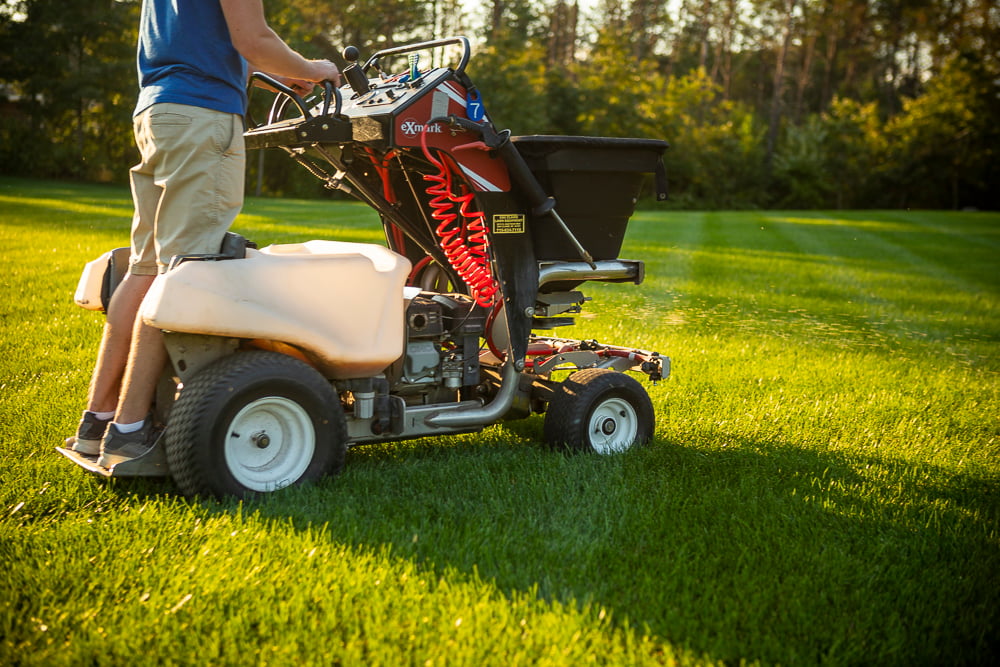 lawn care technician applying granular fertilizer to a nice lawn