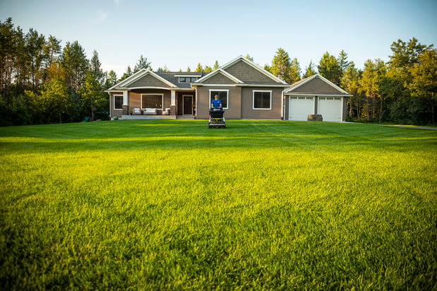 lawn care technician applying fertilizer to nice lawn