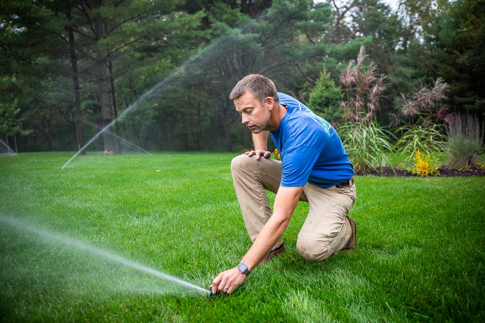 irrigation technician inspects sprinkler system for problems