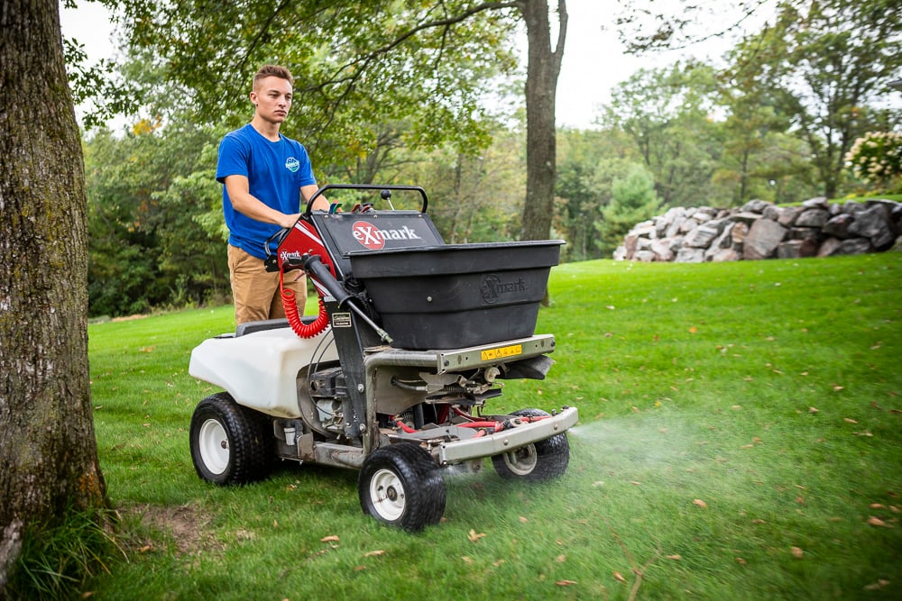 lawn care technician applies liquid fertilizer