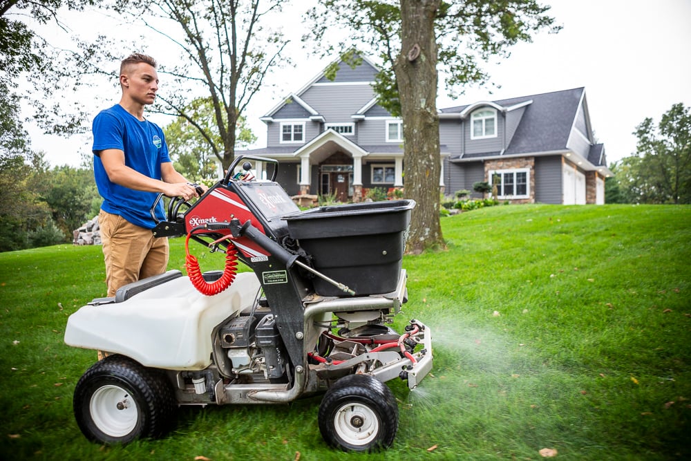 lawn care expert spreads liquid grub control