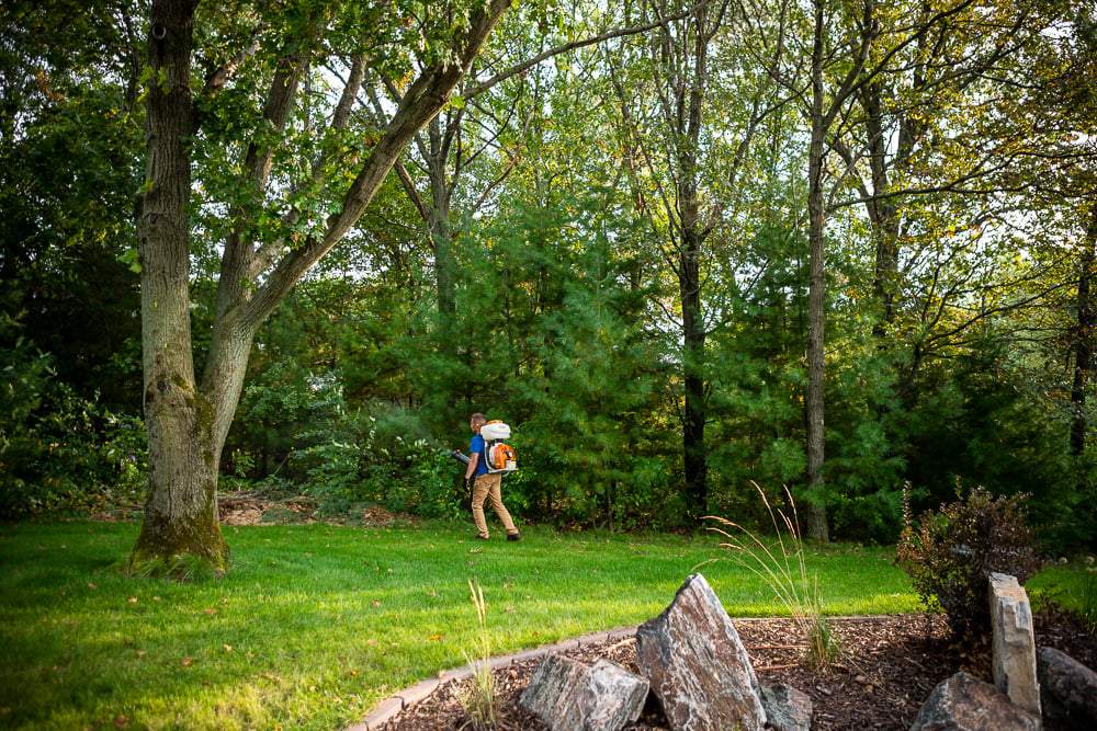 pest control expert sprays near perimeter of yard