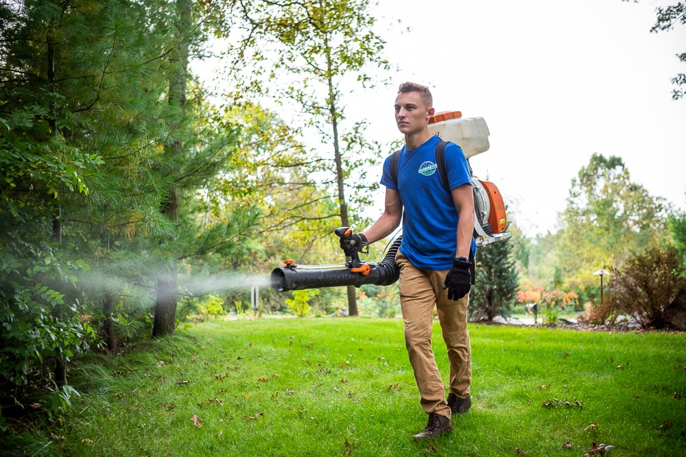 pest control technician sprays for mosquitoes