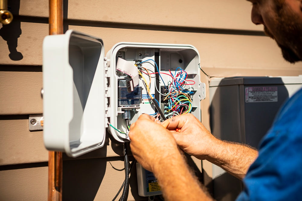 irrigation technician works on sprinkler system controller