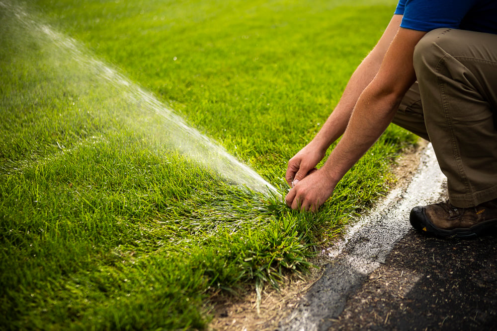 irrigation technician testing and calibrating a lawn sprinkler system