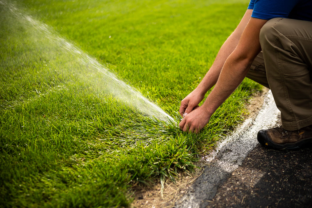 lawn irrigation technician inspecting irrigation system