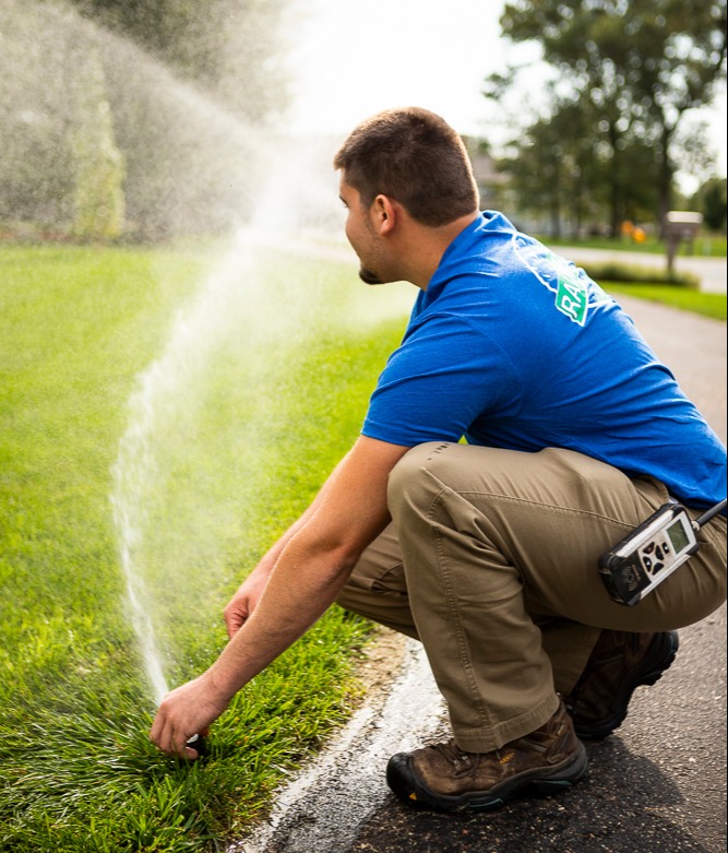 irrigation technician adjusts sprinkler head