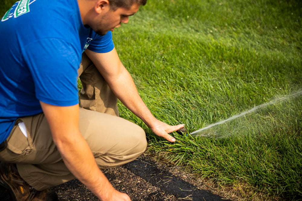 irrigation team adjusts sprinkler head
