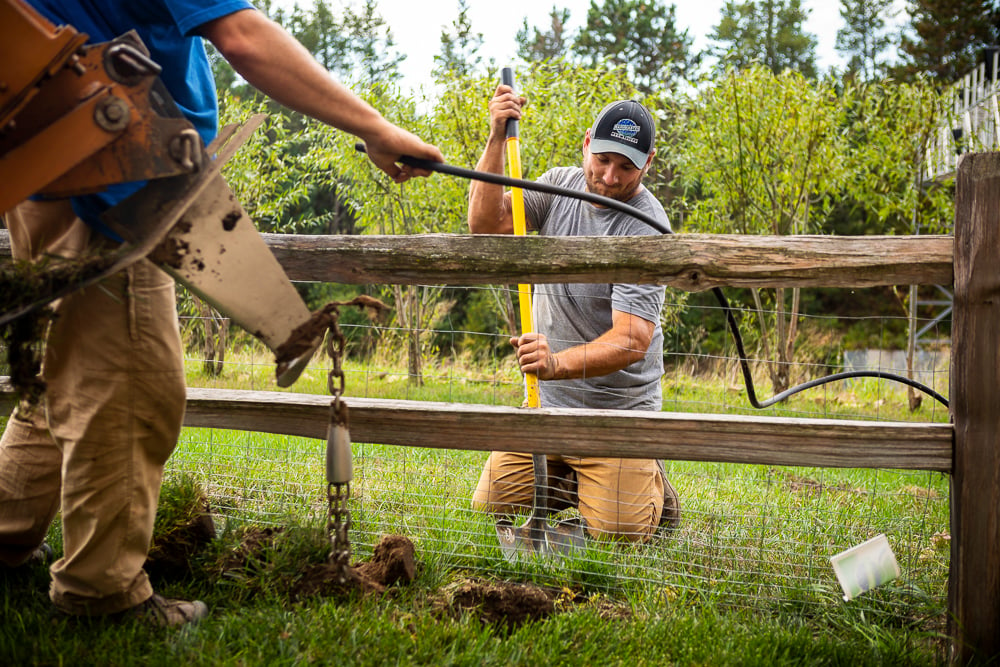 irrigation team installs sprinkler system around fence