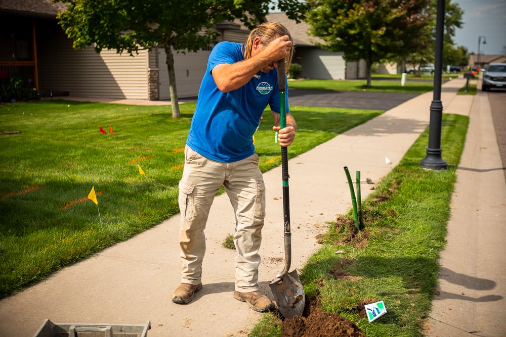 irrigation technician digs hole to install sprinkler head