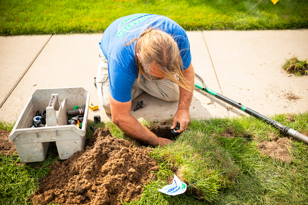 irrigation technician repairs sprinkler head