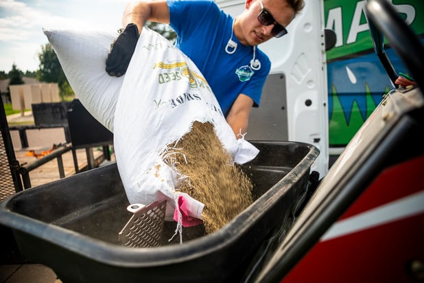 RainMaster lawn care technician pouring bag of grass seed