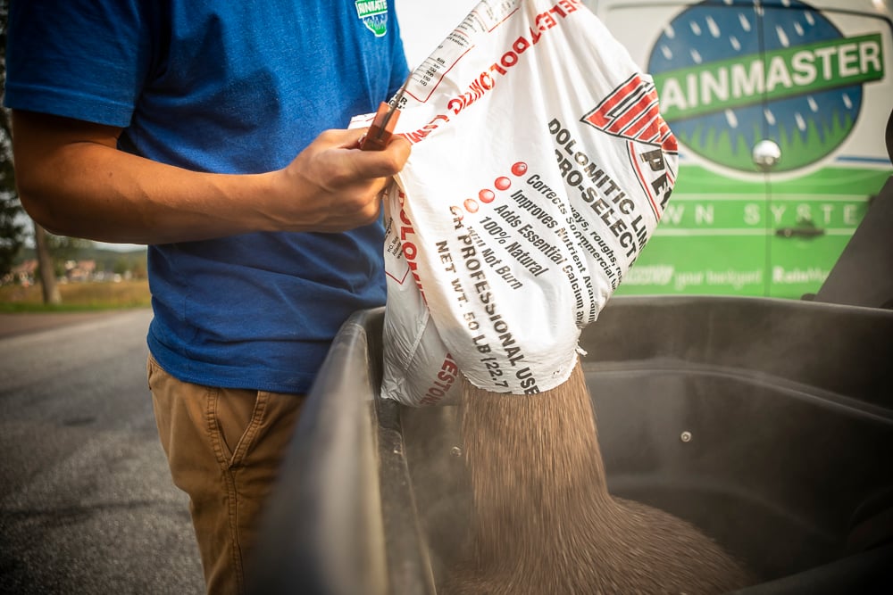 lawn care team pours lime into spreader