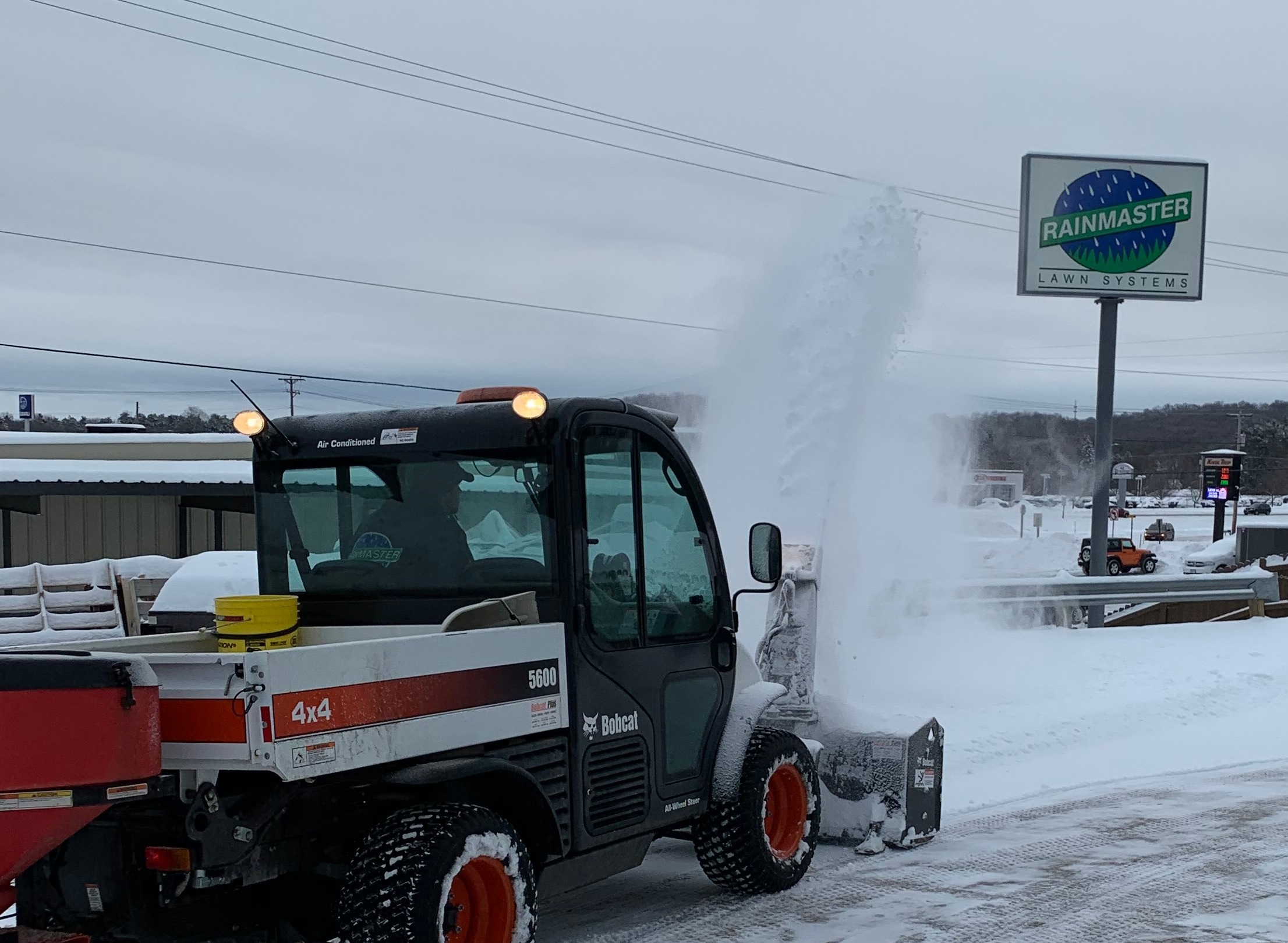 snow removal machine clearing snow from a parking lot with a powered snowblower