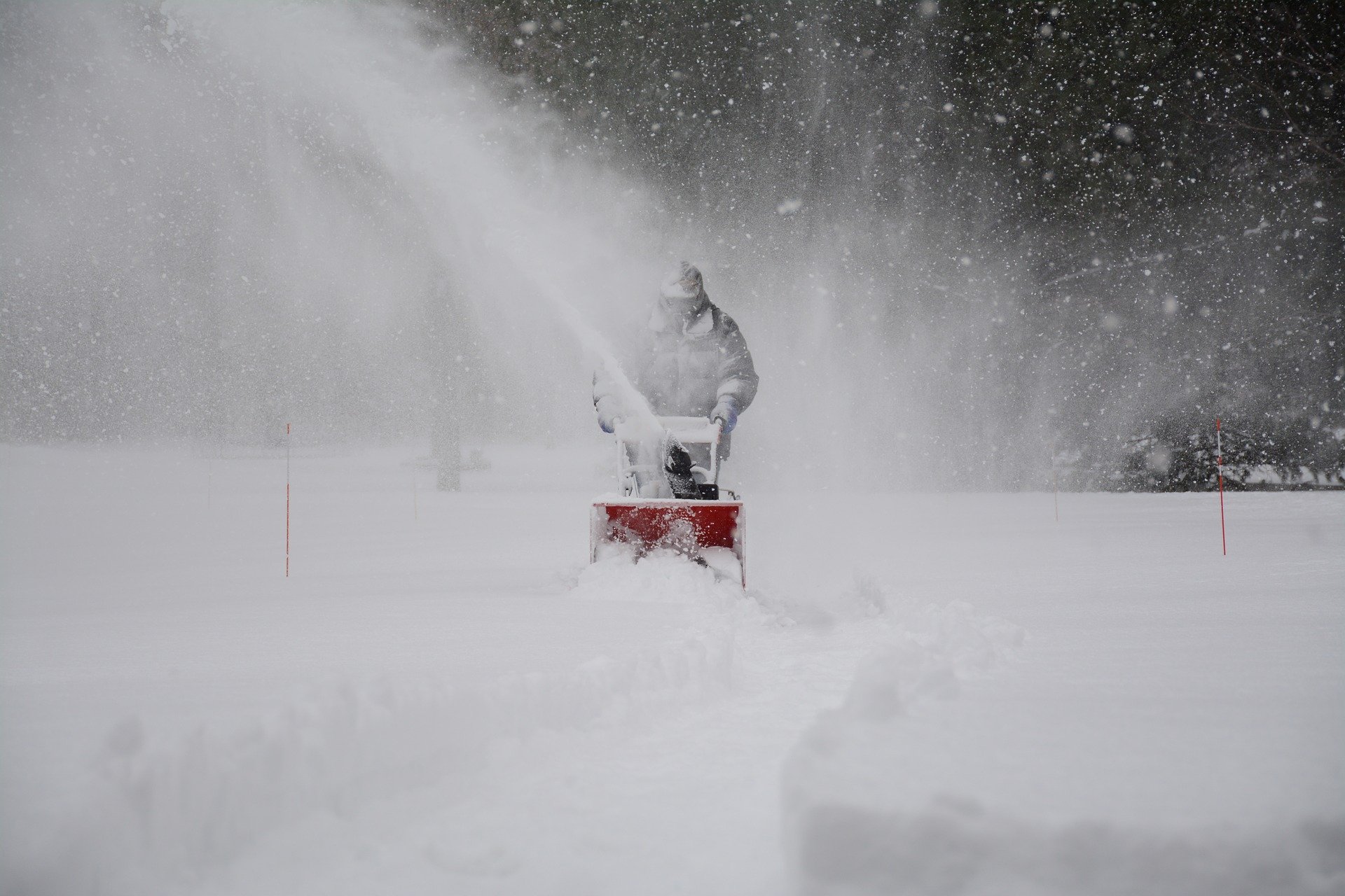 snow removal technician running a snowblower in a blizzard