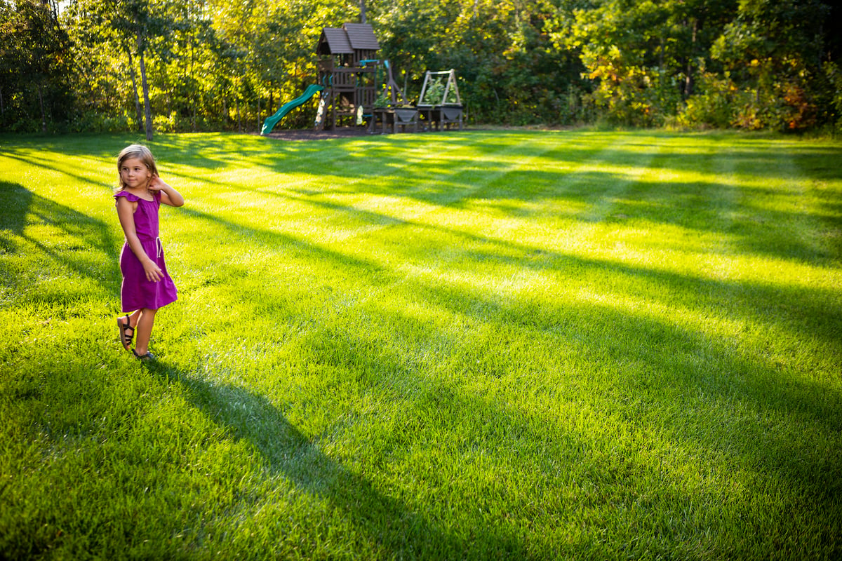 child stands in healthy green grass