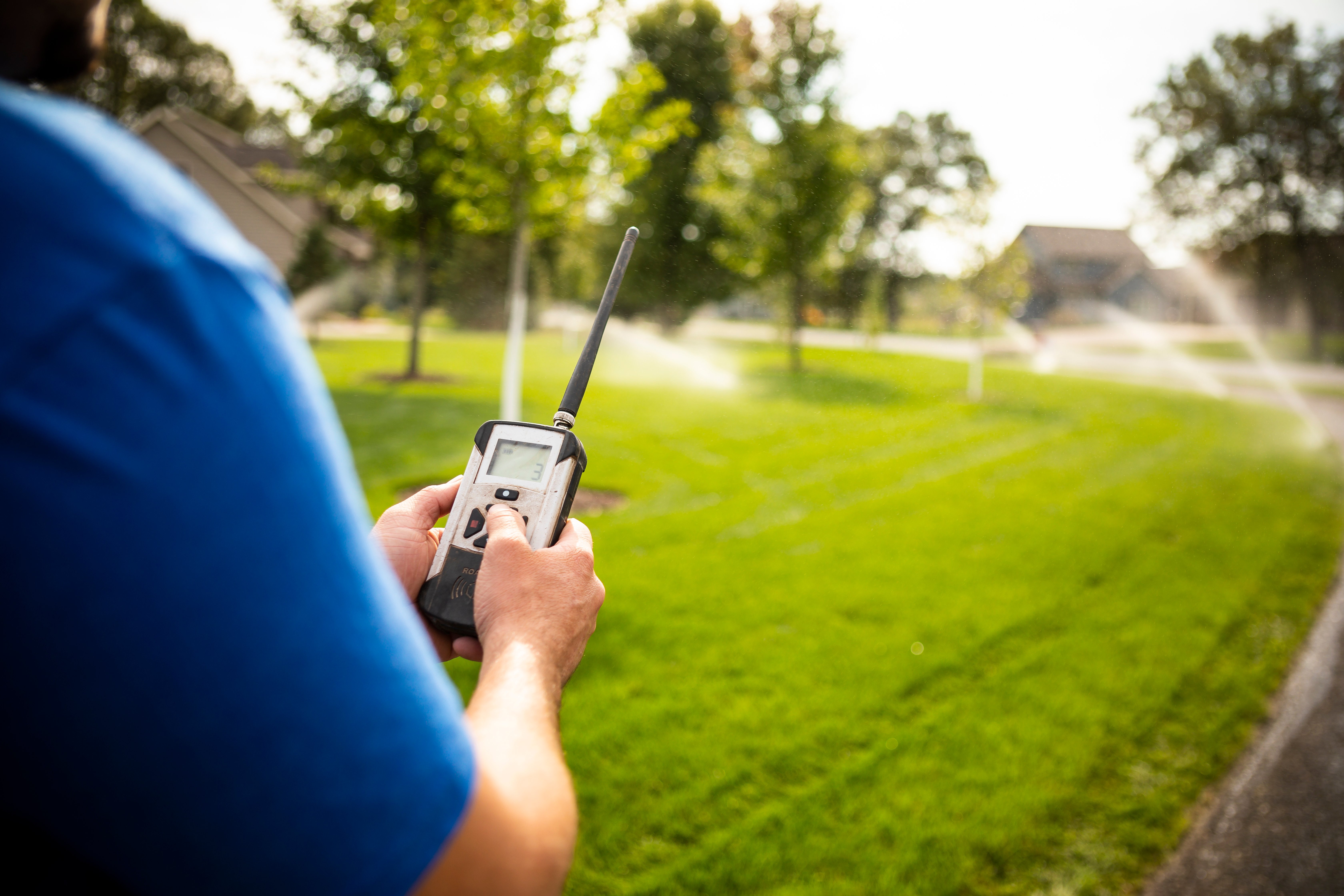 irrigation maintenance technician testing a lawn sprinkler system with a remote control