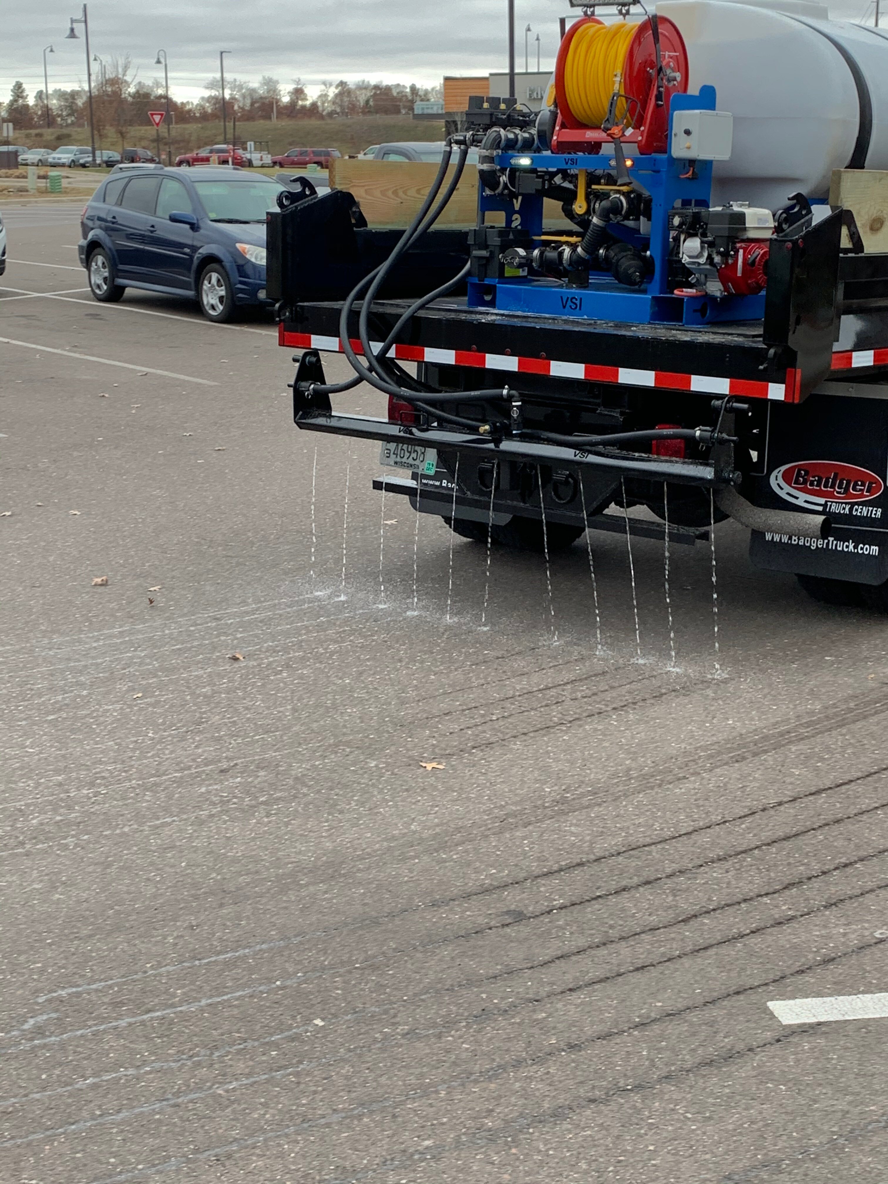 snow removal truck spraying salt brine on a parking lot before a snowstorm