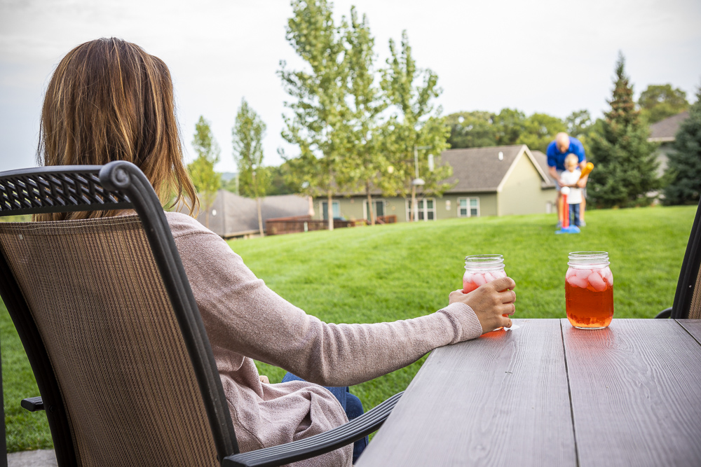 customer relaxes outside and watches her family play