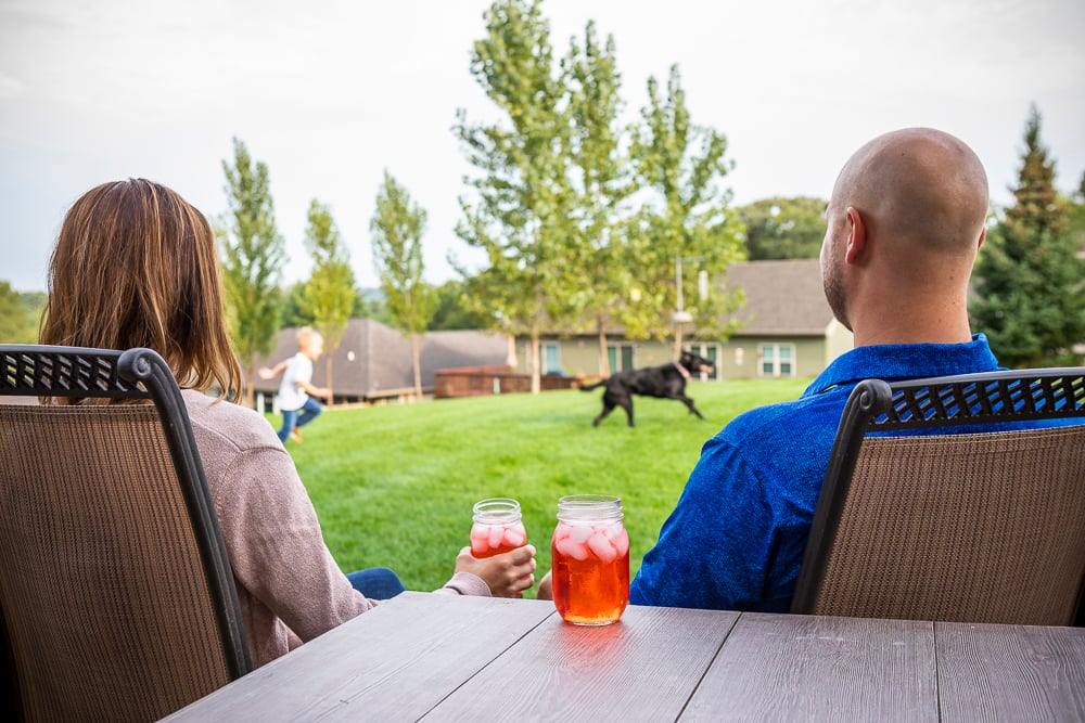 parents sit and and watch family play on healthy lawn