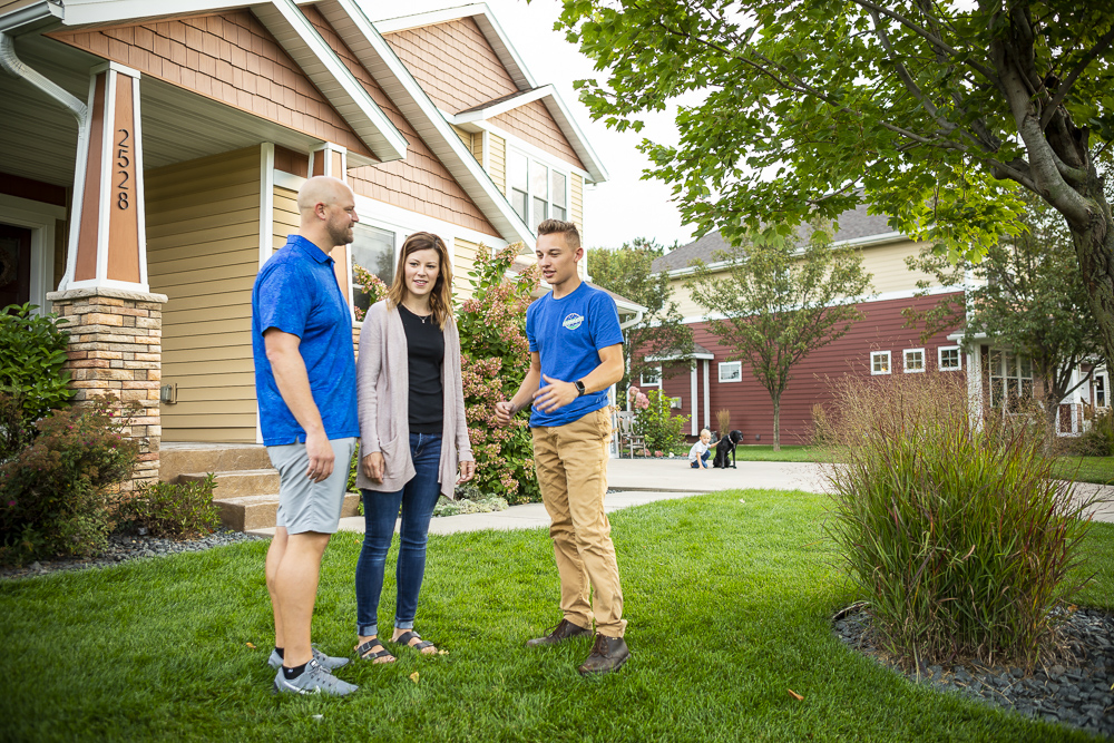 lawn care technician and customers discussing project