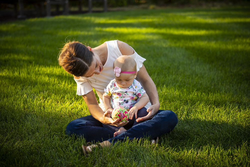 mom and baby sit on thick healthy grass 