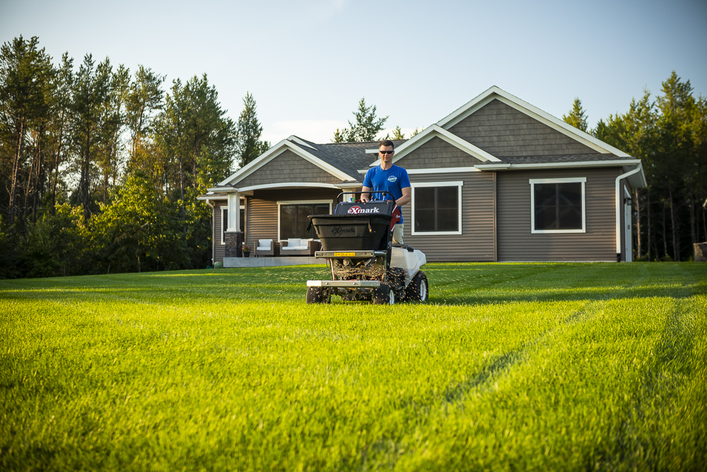 lawn care technician fertilizes lawn