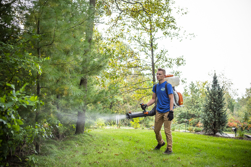 pest control technician sprays for mosquitoes