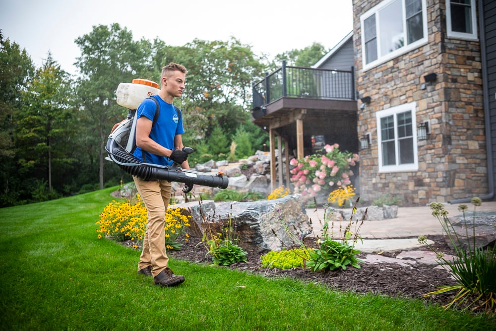 pest control technician sprays for mosquitoes