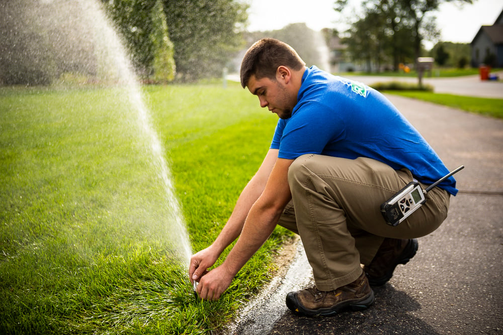 irrigation technician adjusts sprinkler head