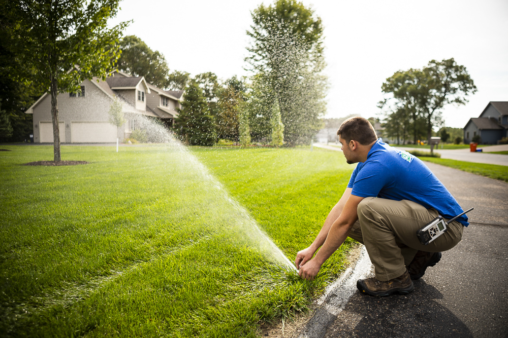 irrigation technician adjusts sprinkler head