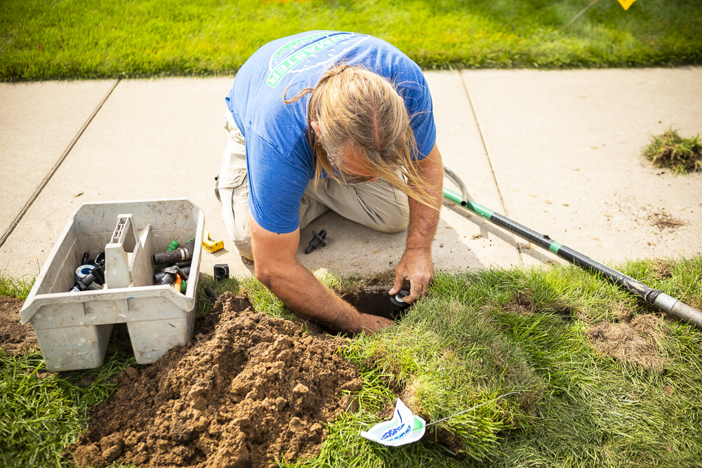 irrigation technician repairs sprinkler head 